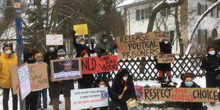 Demonstranten mit Plakaten vor einer alten Villa