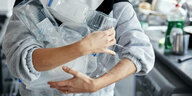 Eine Frau steht in einer Küche und hält Plastikverpackungen im Arm
