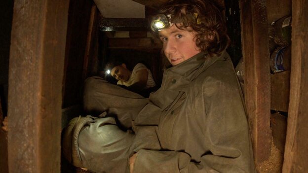 Rory Hooper in einem Engen Tunnel mit Stirnlampe Rory Hooper in einem Engen Tunnel mit Stirnlampe