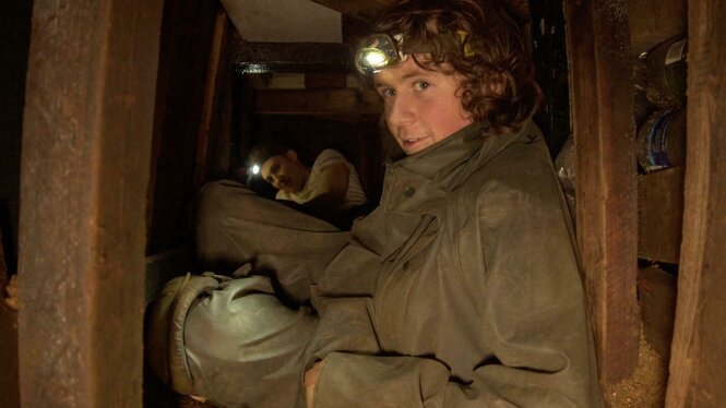 Rory Hooper in einem Engen Tunnel mit Stirnlampe