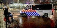 Polizisten im Streifenwagen sprechen eine Frau an, die am Abend noch in Rotterdam unterwegs ist
