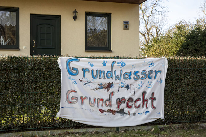 Ein Transparent mit der Aufschrift "Grundwasser Grudrecht" hängt an einem gartenzaun