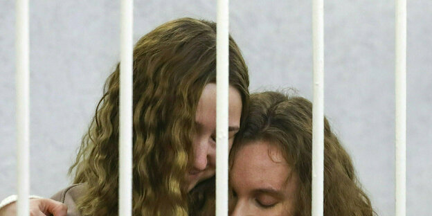 die Journalistinnen Katerina Bachwalowa und Daria Tschulzowa hinter weißen Gittern liegen sich in den Armen