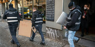 Polizisten tragen bei der Großrazzia Kisten aus einem Haus in Neukölln