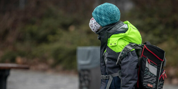 Ein Junge mit Maske geht auf einer Straße Ein Junge mit Maske geht auf einer Straße
