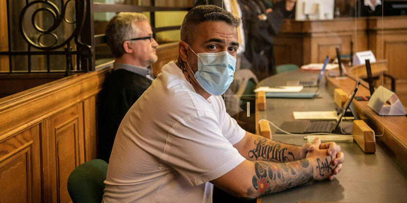 Der Rapper Bushido sitzt in einem Gerichtssaal mit Maske. Neben ihm sitzt sein Anwalt.