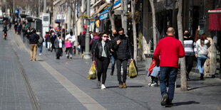 Menschen tragen Einkaustüten in einer Einkaufsstraße in Jerusalem