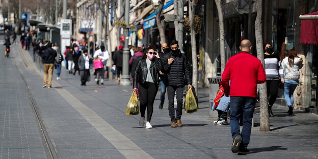 Menschen tragen Einkaustüten in einer Einkaufsstraße in Jerusalem
