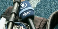 Aufnahmetechnik und ein Mikrofon des NDR liegt auf einem blauen Hallenboden