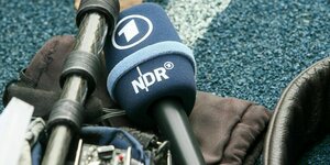 Aufnahmetechnik und ein Mikrofon des NDR liegt auf einem blauen Hallenboden