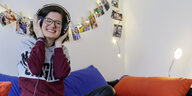Annika Braun sitzt auf dem Sofa, hört Musik und lacht