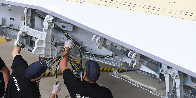 Mitarbeiter von Airbus arbeiten am Flügel eines A350.