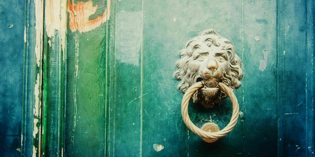 Ein Türklopfer mit Löwenkopf an einer grünen Tür