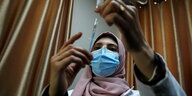 Eine Krankenschwester mit Mundschutz bereitet eine Impfung vor