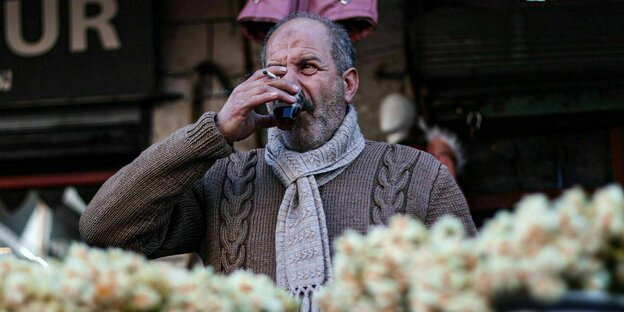 Ein mann trinkt tee an einem Marktstand