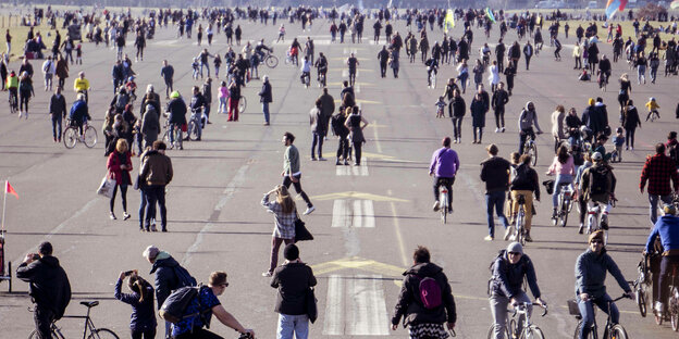 Viele Menschen laufen über eine ehemalige Landebahn auf dem Flughafenpark Tempelhof