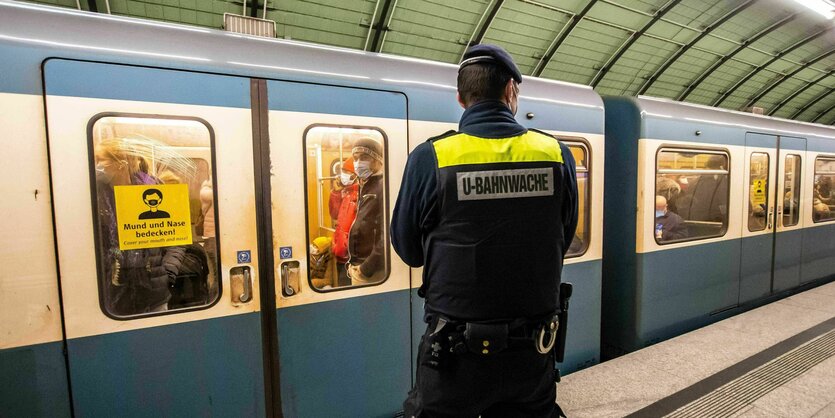 Uniformierter Mann steht auf einem Bahnsteig, auf dem eine Bahn steht