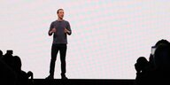 Mark Zuckerberg steht auf einer Bühne, vor ihm als Scherenschnitt Zuschauer