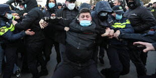 Eine Prerson wird bei einer Demonstration von Polizisten verhaftet.