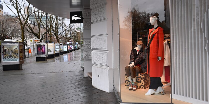 Das Bild zeigt das Schaufenster eines Modegeschäfts an einer leeren Straße.