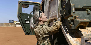Eine Soldatin steht vor einem Militärfahrzeug