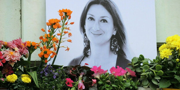 Blumen stehen im Gedenken vor einem Foto der ermordeten maltesischen Journalistin Daphne Caruana Galizia