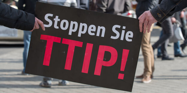 Demonstranten halten ein Schild mit der Aufschrift "Stoppen Sie TTIP!