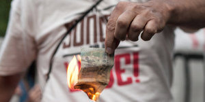 Ein Mann hält einen brennenden Euroschein