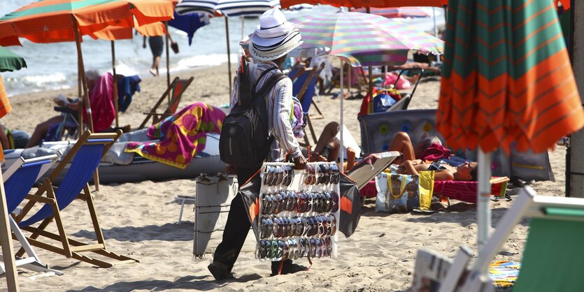 Strandverkäufer zwischen Urlauber*innen