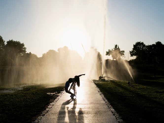 Silhouette einer tanzenden Frau vor Wasserfontänen