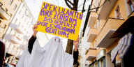 Ein als Gespenst verkleidete Aktivist:in hält auf einer Berliner Straße ein Schild hoch auf dem steht: "Spekulanten eure Zeit ist um. Das Gespenst der Enteignung geht um!"
