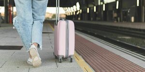 Eine frau mit einem Koffer am Bahnsteig