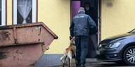 Ein Polizist mit einem Drogenspürhund geht in ein Wohnhaus