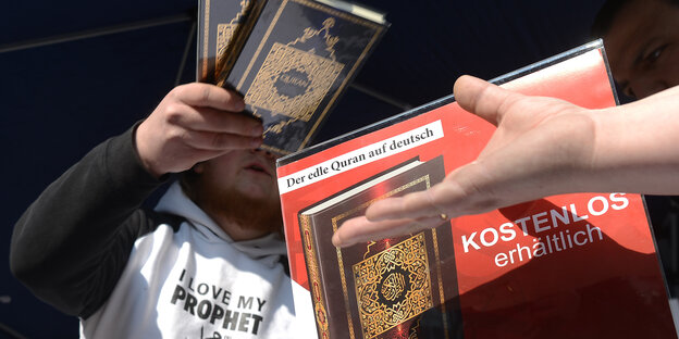 Ein Mann verteilt auf der Straße eine Koran-Ausgabe