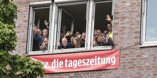 Rekateur*innen der taz nord winken aus dem geöffneten Fenster