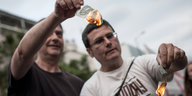 Zwei Männer halten brennende Euroscheine in der Hand