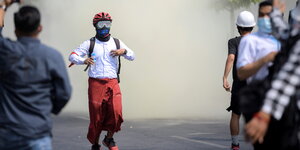 Vermummter Demonstrant tritt aus dem Rauchnebel
