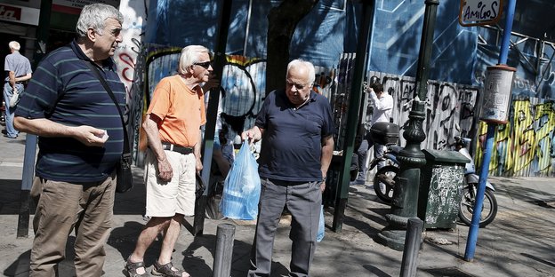 Drei Männer warten in Athen auf den Bus