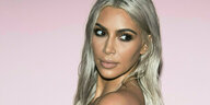 Kim Kardashian post vor einer rosa Wand