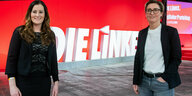 Janine Wissler und Susanne Hennig-Wellsow stehen vor einem Schirftzug "Die Linke"r stehen vor einer roten Wand