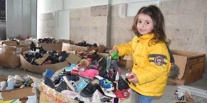 Ein armenisches Flüchtlingsmädchen aus Berg Karabach vor einer Kiste mit Spenden