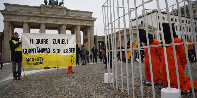 Demonstranten halten ein Plakat hoch, in dem sie die Schließung Guantanamos fordern.