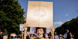 Eine Demonstrantin hält ein Schild mit der Aufschrift "Decolonize your Mind" (Übersetzung: Dekolonisiere dein Bewusstsein)