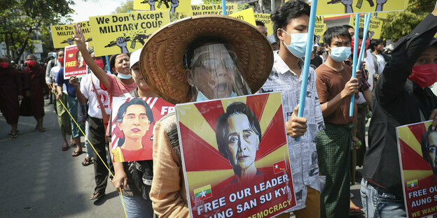 Menschen in Myanmar demonstrieren mit umgehängten Schildern für die Freilassung von Aung San Suu Kyi