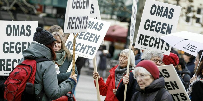 Eine Gruppe von älteren Frauen steht beisammen mit Transparenten, auf denen steht "Omas gegen Rechts"