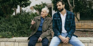 Links Noah Klieger, rechts Takis Würger, beide sitzen auf einer Mauer in Tel Aviv