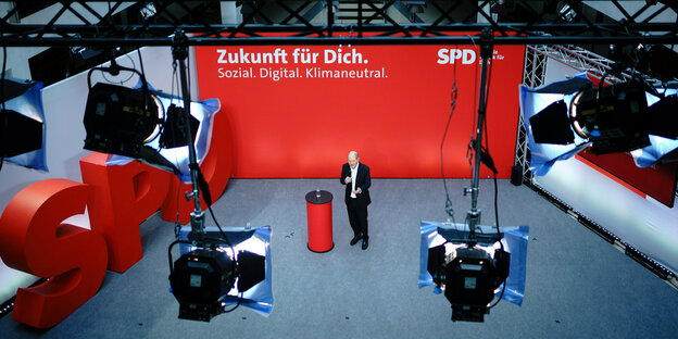 Scheinwerfer sind auf Olaf Scholz gerichtet. Ein rotes Plakat mit der Schrift "Zukunft für Dich Sozial.Digital.Klimaneutral