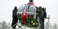 Drei Polizisten stehen auf den Kufen eines fliegenden Hubschraubers
