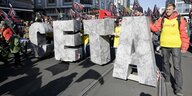 Demonstranten mit großen CETA Buchstaben auf einer Straße in Berlin