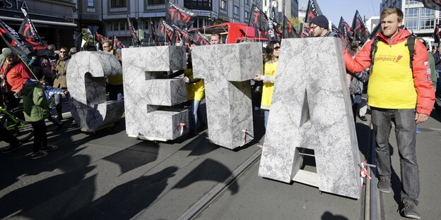 Demonstranten mit großen CETA Buchstaben auf einer Straße in Berlin